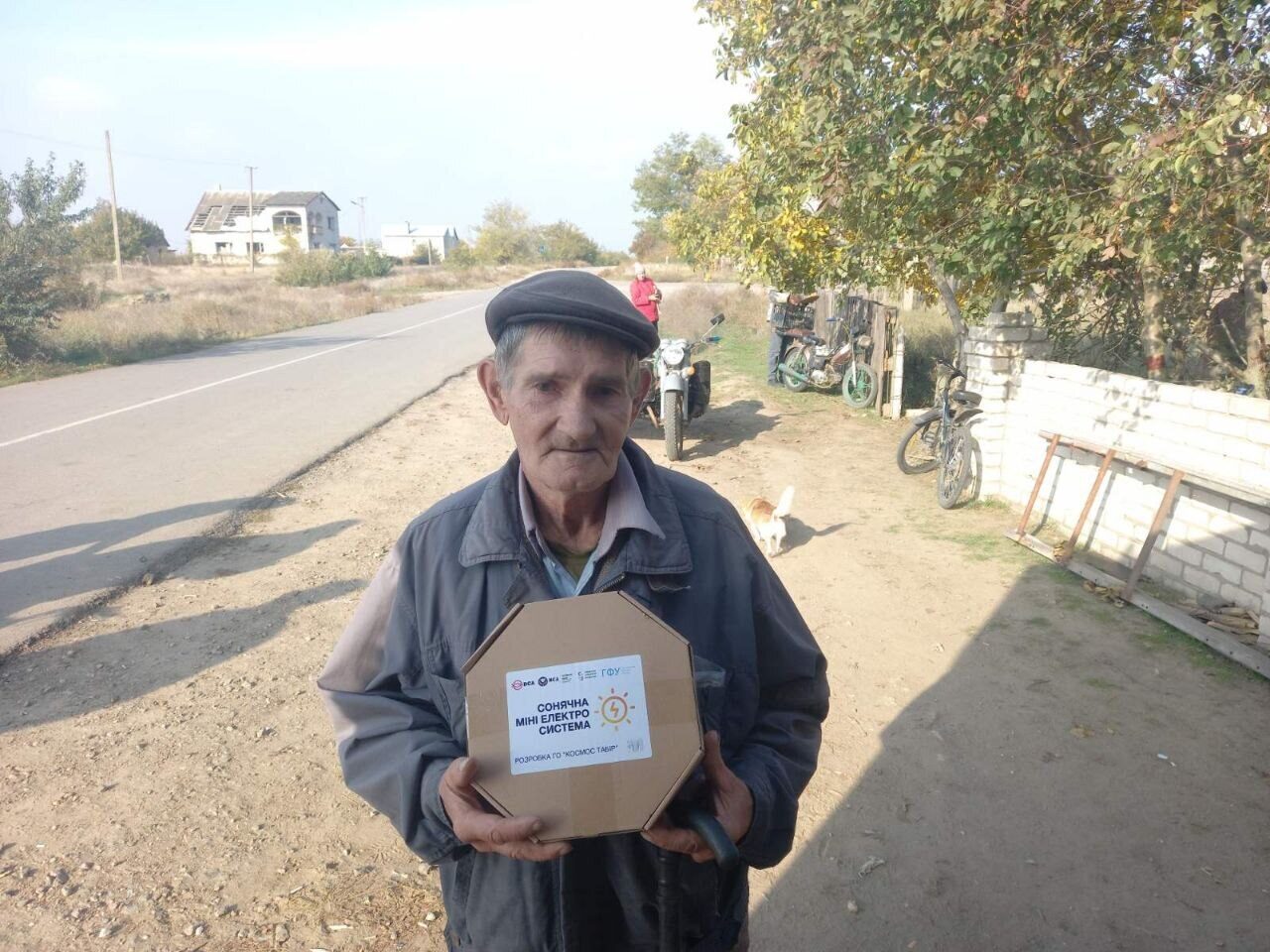 An elderly man in a cap holds a MINISOLAR box