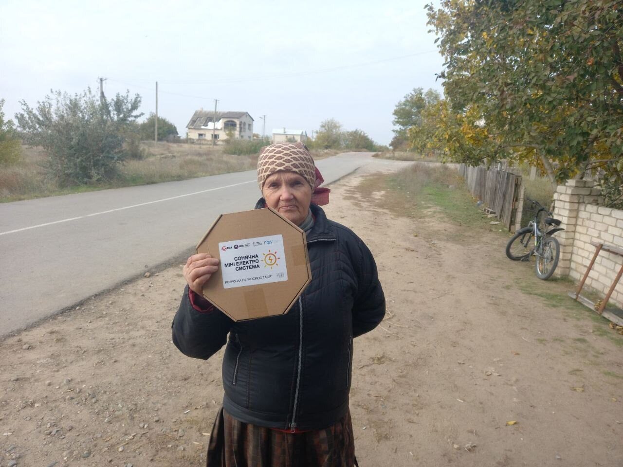 A woman holds a MINISOLAR box on a village road