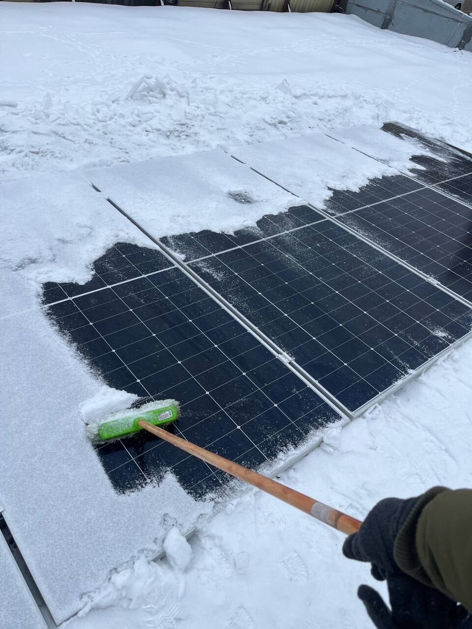 Snow is brushed off solar panels