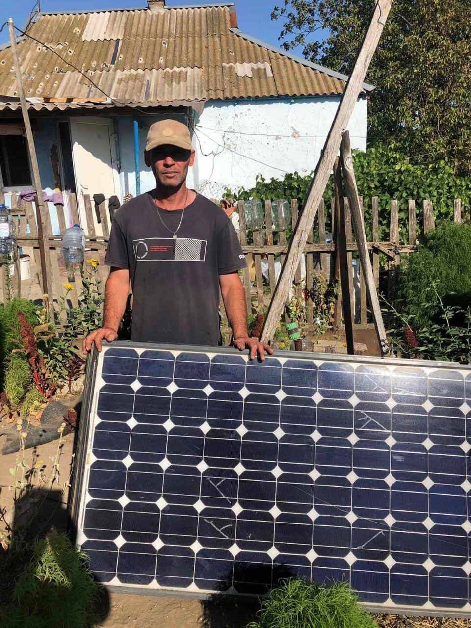 A man holds a solar panel in a garden